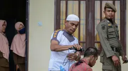 Seorang anak Punk dicukur rambutnya oleh petugas kepolisian di Banda Aceh (9/1). Indonesia merupakan negara yang memiliki populasi punk terbesar di dunia. (AFP Photo/Chaideer Mahyuddin)