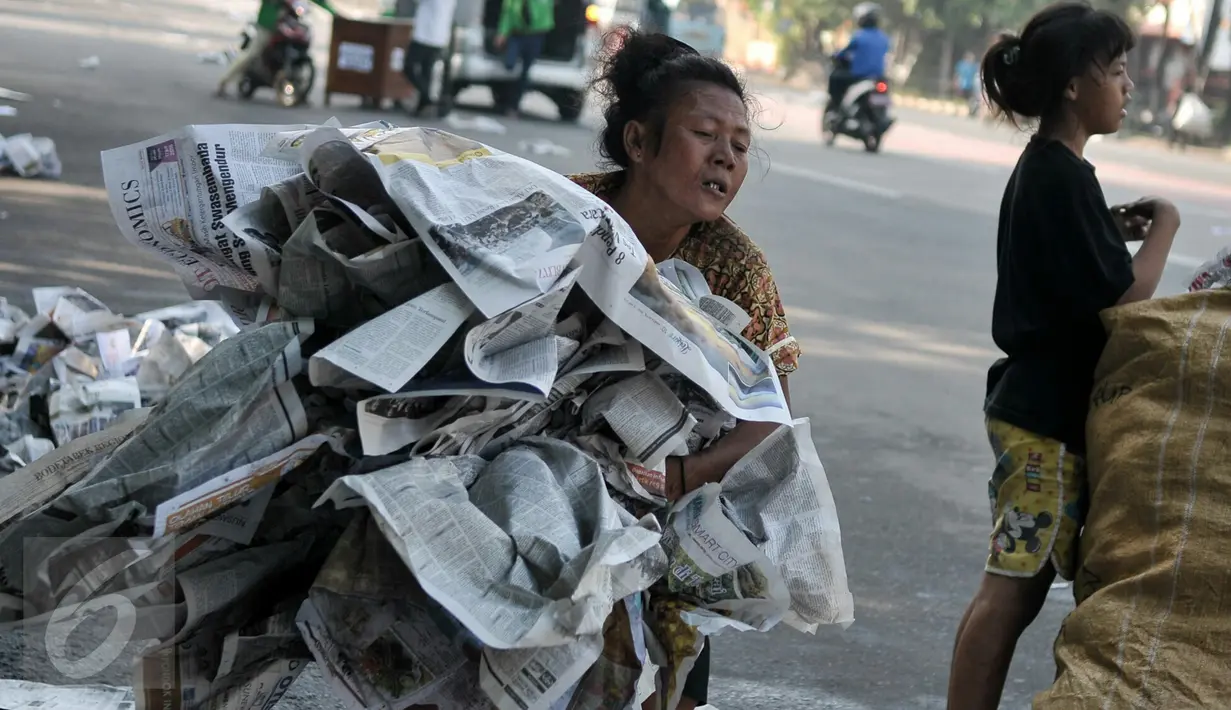 Seorang ibu bersama anaknya mengumpulkan koran yang digunakan sebagai alas, Jatinegara, Jakarta, Rabu (6/7/2016). Usai ribuan warga menunaikan salat Id, tumpukan koran berserakan dimana-mana. (Liputan6.com/Yoppy Renato)