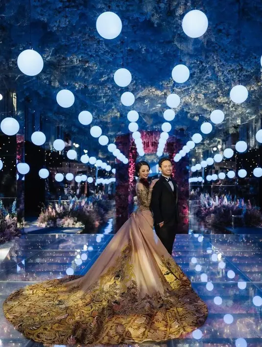Berbeda dengan akad nikah yang kental nuansa adat, momen resepsi ini digelar cenderung modern dengan desain tata panggung megah bak taman bunga di luar angkasa. (Instagram/thebridedept).