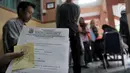 Salah seorang ibu menunjukkan nomor antrean pengambilan token PPDB di SMPN 92, Jakarta, Senin (25/6). Meski dibuka pada pada pukul 08.00 WIB, para orang tua calon siswa baru sudah mendatangi sekolah sejak pukul 6 pagi. (Merdeka.com/Iqbal S Nugroho)