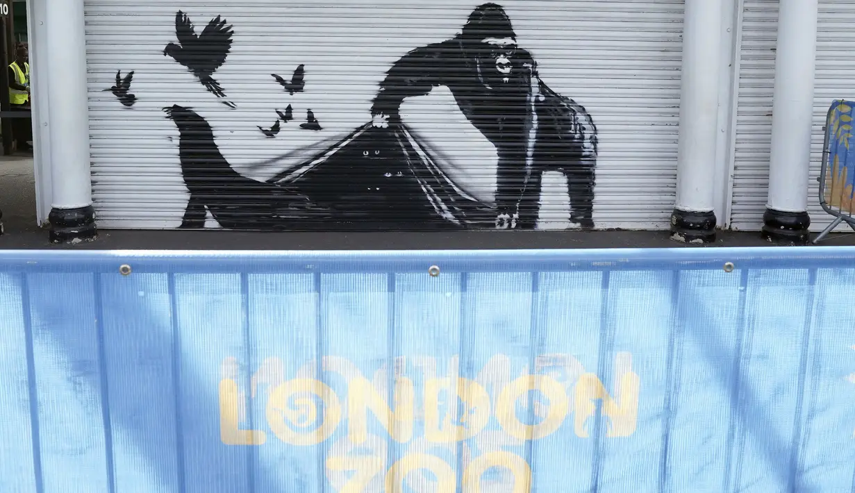 Sebuah mural karya seniman jalanan yang sulit dipahami, Banksy, menunjukkan seekor gorila yang memegang gerbang masuk sementara burung-burung terbang dan seekor singa laut melenggang pergi.  (Stefan Rousseau/PA via AP)