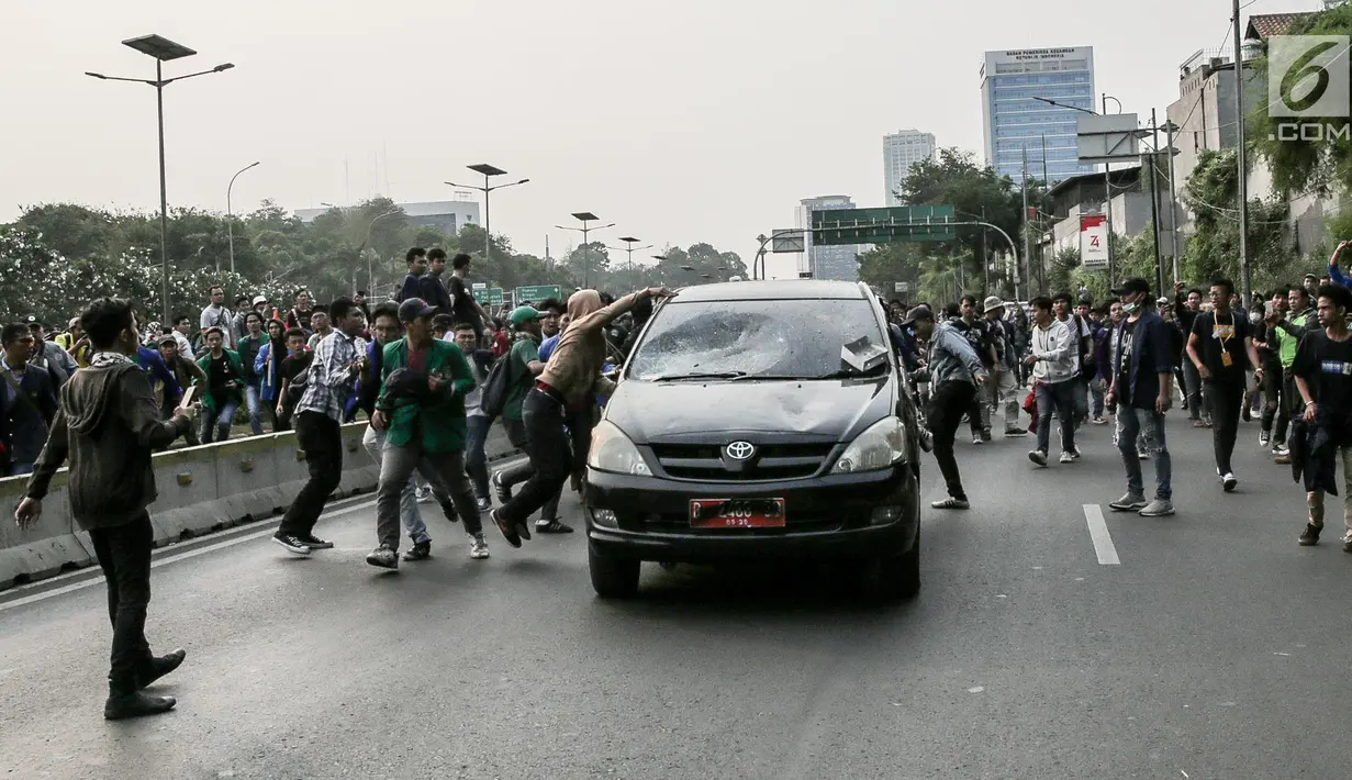 Massa aksi  melakukan penyerangan terhadap mobil pelat nomor merah yang melintasi jalan tol seberang Gedung DPR/ MPR RI, Jakarta, Selasa (24/9/2019). Selain menutup ruas tol, kendaraan dinas pemerintah dan milik polisi jadi korban pelemparan dan perusakan oleh mahasiswa. (Liputan6.com/Faizal Fanani)
