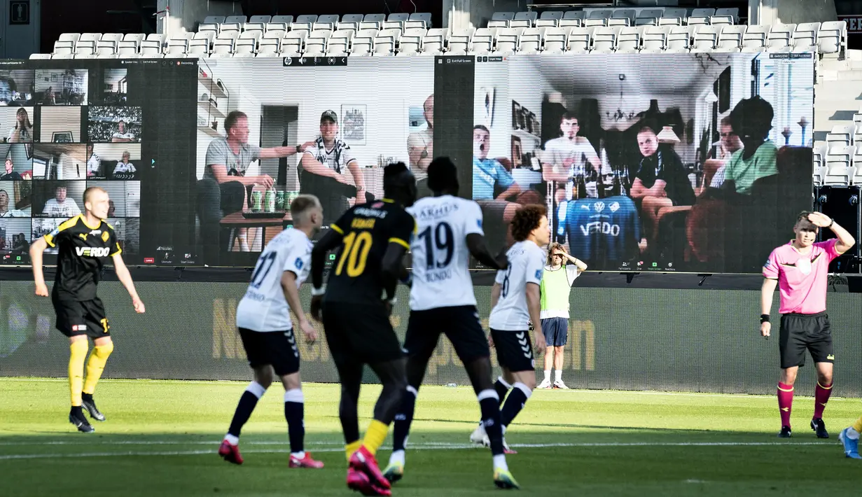 Penonton menyaksikan pertandingan Liga Denmark antara AGF dengan Randers FC melalui aplikasi video conference di Ceres Park, Aarhus, Denmark, Kamis (28/5/2020). Laga ini menjadi pertandingan pertama yang melibatkan suporter melalui aplikasi pertemuan virtual. (Henning Bagger/Ritzau Scanpix via AP)