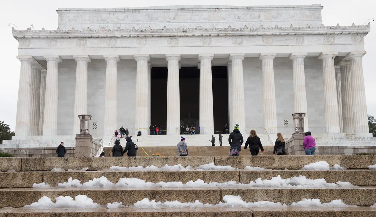 Pengunjung menaiki tangga Lincoln Memorial di Washington yang tertutup salju, Selasa (14/3). Badai salju menerjang kawasan Amerika Serikat timur laut, dari West Virginia hingga Maine, menyebabkan hujan salju lebat di sejumlah tempat. (Tasos Katopodis/AFP)