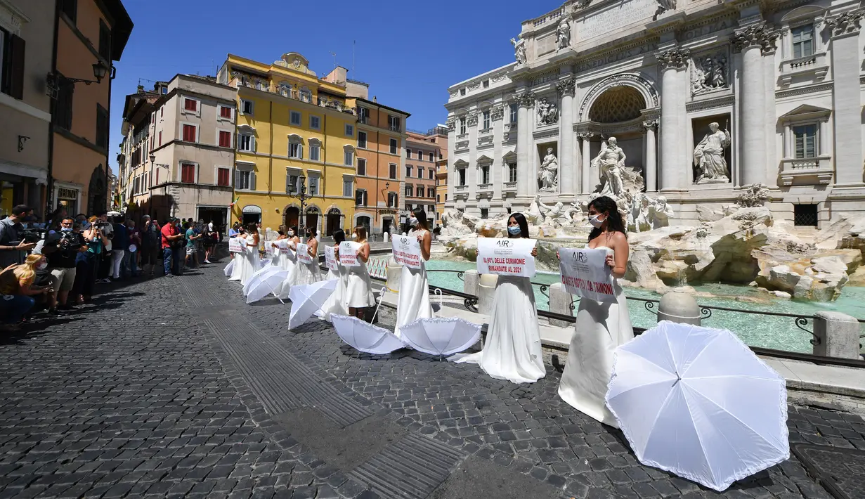 Pengantin perempuan yang mengenakan gaun pernikahan mereka melakukan flashmob saat aksi protes di Trevi Fountain, Roma, Selasa (7/7/2020). Mereka memprotes kebijakan pemerintah Italia yang masih melarang adanya acara pernikahan, meski penerapan lockdown sudah dilonggarkan. (Tiziana FABI/AFP)