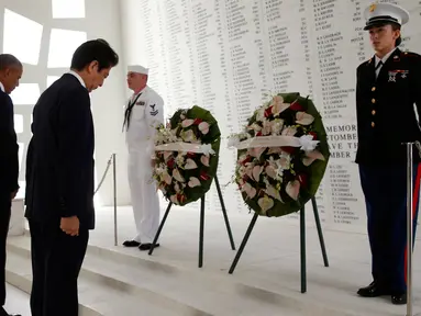 Presiden AS, Barack Obama dan PM Jepang, Shinzo Abe menundukan kepala saat upacara peletakan karangan bunga di atas kapal USS Arizona Memorial Perang Dunia II di Joint Base Pearl Harbor-Hickam, Hawaii, (27/12). (REUTERS/Kevin Lamarque)