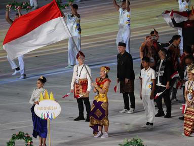 Atlet renang putri, Flairene Candrea Wonomiharjo tampil sebagai pembawa bendera Kontingen Indonesia dalam upacara pembukaan SEA Games 2023 di Morodok Techo Stadium, Phnom Penh, Kamboja, Jumat (5/5/2023) malam WIB. Peraih medali emas pada SEA Games 2021 di Vietnam itu melangkah pasti memimpin Kontingen Indonesia dalam defile negara peserta. (Bola.com/Abdul Aziz)