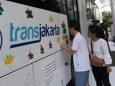 Seorang anak berkebutuhan khusus melukis bus Transjakarta di halaman Balai Kota, Jakarta, Jumat (20/4). Kegiatan tersebut dalam rangka memperingati Hari Kartini. Tema lukisan yang diangkat adalah ‘Ibuku Perempuan Tangguh’. (Liputan6.com/Arya Manggala)