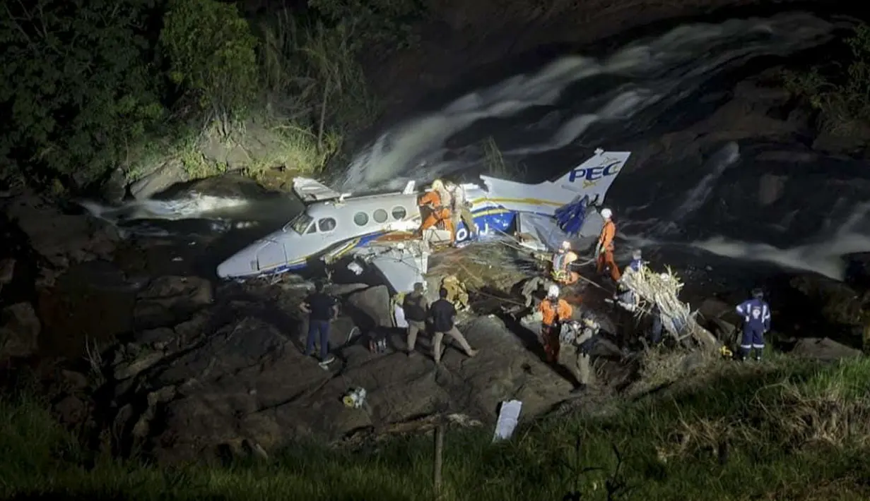 Petugas pemadam kebakaran berada di dekat puing-puing pesawat jatuh yang ditumpangi penyanyi Brasil Marilia Mendonca di Caratinga, pada 5 November 2021. Lima orang, termasuk sang penyanyi, meninggal dalam kecelakaan tersebut. (Minas Gerais Fire Department / AFP)