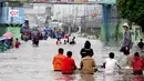 Seorang penguna jasa gerobak saat melintasi banjir di Jalan Gunung Sahari, Jakarta, Senin (6/2/2015). Jasa gerobak Mematok harga Rp. 30 ribu untuk membawa motor sedangkan untuk per orang hanya Rp. 10 ribu. (Liputan6.com/Faizal Fanani)