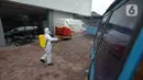Petugas menyemprotkan cairan disinfektan kendaraan pelayanan Suku Dinas Sosial Jakarta Timur, Jumat (18/2/2022).  Sebanyak 6 orang yang terpapar Covid-19 sedang menjalani isolasi di rumah, sementara pelayanan ditutup selama tiga hari. (merdeka.com/Imam Buhori)