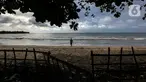 Seseorang terlihat di pantai Carita, Pandeglang, Banten, Selasa (18/1/2022). Objek wisata Pantai Carita yang menjadi tempat favorit pengunjung kini tampak sepi seusai gempa beberapa waktu lalui dan juga lantaran naikknya kasus virus covid 19 varian omicron. (Liputan6.com/Johan Tallo)