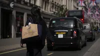 Seorang perempuan membawa tas belanja yang dapat digunakan kembali melintasi distrik perbelanjaan Regent Street, di London, Rabu (18/5/2022). Kantor Stastitik Nasional (ONS) Inggris mengatakan inflasi indeks harga konsumen meningkat menjadi 9% dalam 12 bulan hingga April, dari 7% pada bulan Maret. (AP Photo/Matt Dunham)