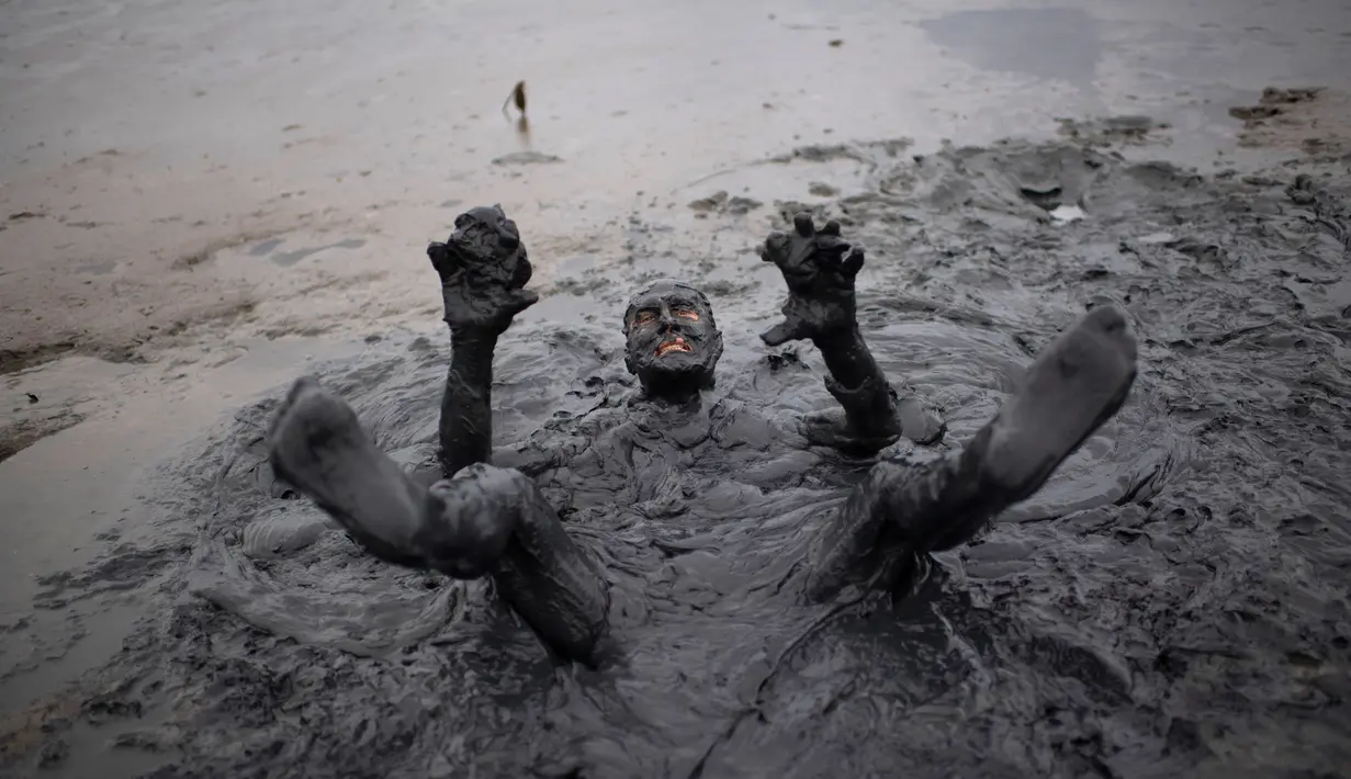 Seorang peserta berendam saat mengikuti Bloco da Lama", pesta mandi lumpur di Paraty, negara bagian Rio de Janeiro, Brasil (2/3). "Bloco da Lama" diketahui sudah ada sejak 1986 lalu. (AFP Photo/Mauro Pimentel)