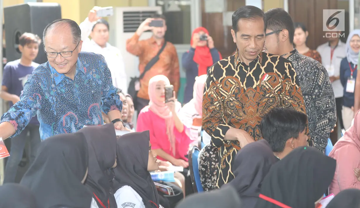 Presiden Bank Dunia, Jim Yong Kim membagikan buku tulis didampingi Presiden Joko Widodo (Jokowi) saat blusukan di PAUD Desa Tangkil, Kecamatan Caringin, Bogor, Rabu (4/8). Keduanya berangkat usai pertemuan di Istana Bogor (Liputan6.com/Angga Yuniar)