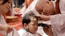 Ekspresi Seorang anak lelaki bernama Budha Myung Bub saat rambutnya dicukur oleh seorang biksu selama kebaktian merayakan ulang tahun ke-2.563 Buddha pada 12 Mei, di Kuil Jogye di Seoul, Korea Selatan, Senin (22/4). Sepuluh anak terpilih menjadi peserta peringatan ini. (AP Photo/Ahn Young-joon)