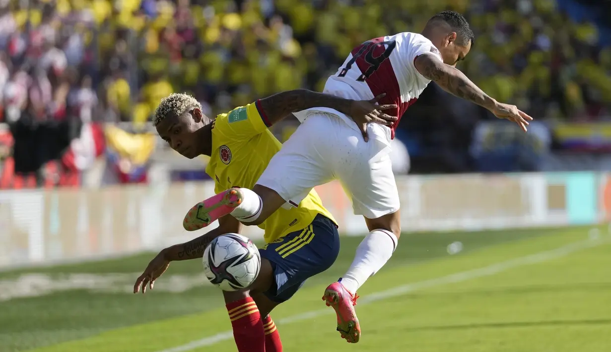 Penyerang Kolombia Hugo Martinez berebut bola dengan gelandang Peru Yoshimar Yotun pada lanjutan fase grup kualifikasi Piala Dunia 2022 zona Amerika Selatan, di Estadio Metropolitano Roberto Meléndez, Sabtu (29/1/2022) dini hari WIB. Peru menang 1-0. (AP Photo/Fernando Vergara)