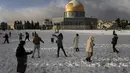 Warga Palestina menikmati salju di sebelah Masjid Kubah Batu di kompleks Masjid Al Aqsa di Kota Tua Yerusalem, Kamis (27/1/2022). Hujan salju yang jarang melanda sebagian wilayah Israel dan Tepi Barat, menutup sekolah dan bisnis. (AP Photo/Mahmoud Illean)