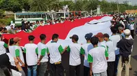 Massa demonstran membentangkan bendera merah putih raksasa di depan Istana Merdeka. Mereka mendesak Jokowi segera melantik pimpinan baru KPK. (Istimewa)