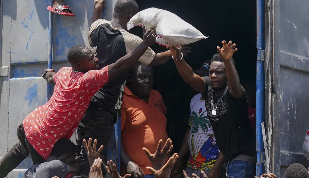 Seorang pria membuang sekantong beras dari trailer truk berisi perbekalan di Vye Terre, Haiti, Jumat (20/8/2021). Bantuan swasta dan kiriman dari pemerintah AS dan lainnya tiba di semenanjung barat daya negara itu yang dilanda gempa 7,2 gempa berkekuatan 14 Agustus. (AP Photo/Fernando Llano)