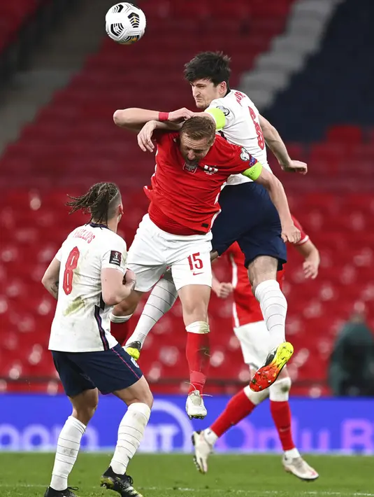 Pemain Inggris Harry Maguire (atas) memperebutkan bola udara dengan pemain Polandia Kamil Glik pada pertandingan Grup I kualifikasi Piala Dunia 2022 di Stadion Wembley, London, Inggris, Rabu (31/3/2021). Inggris menang dengan skor 2-1. (Andy Rain/Pool via AP)