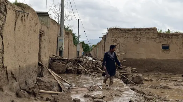 Seorang pria Afghanistan berjalan di dekat rumahnya yang rusak akibat banjir besar di Provinsi Baghland, Afghanistan, Sabtu (11/5/2024).
