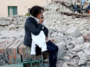 Seorang wanita duduk di antara puing bangunan yang rusak setelah gempa 6,2 SR di Amatrice, Italia tengah, Kamis (24/8). Gempa pada dini hari itu menyebabkan kerusakan besar dan getarannya membuat panik penduduk yang sedang tertidur. (REUTERS/Remo Casilli)