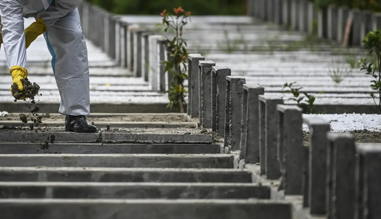 Seorang relawan yang mengenakan setelan alat pelindung diri (APD) menguburkan tubuh seseorang yang diduga meninggal akibat virus corona Covid-19 di sebuah pemakaman, di Yangon  (26/10/2020). (AFP/Ye Aung Thu)