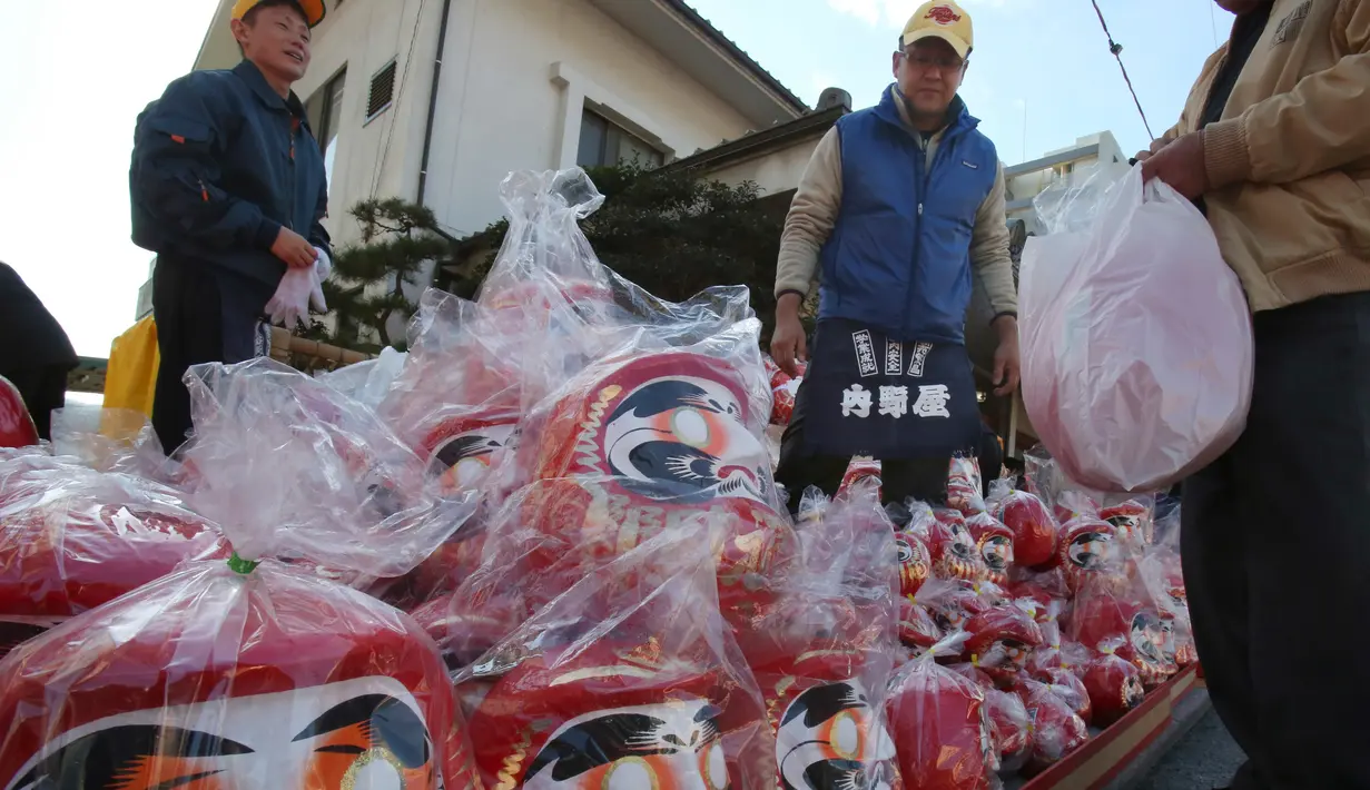 Seorang pedagang menjajakan boneka merah Daruma dalam pameran tahunan Oume Daruma di Tokyo, Jepang, 12 Januari 2018. Boneka ini biasanya dicat dengan warna merah lantaran warna merah dianggap memiliki kekuatan menolak bala.. (AP/Koji Sasahara)