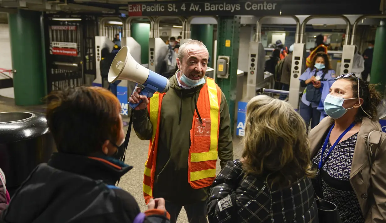 Seorang pejabat MTA membantu mengarahkan penumpang di stasiun kereta bawah tanah di New York, 12 April 2022. Sejumlah orang terluka dalam penembakan yang terjadi pada jam sibuk. (AP Photo/Seth Wenig)