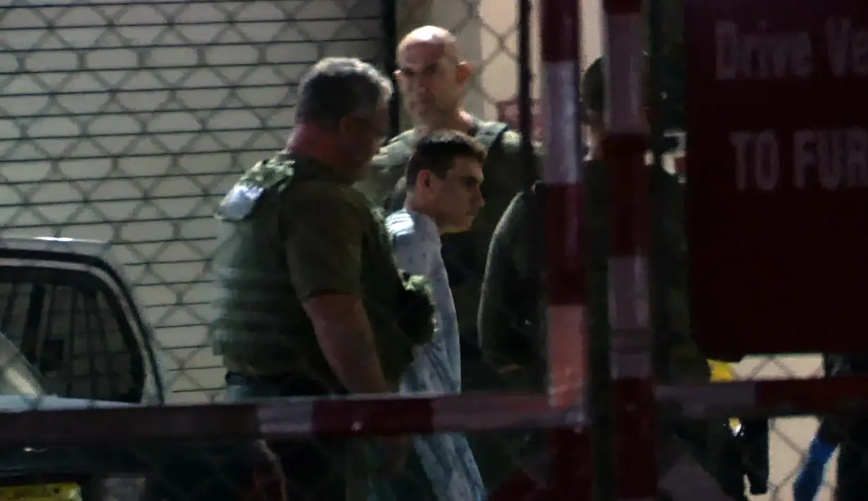 Pelaku penembakan massal di Florida, Nikolas Cruz dibawa petugas saat ditahan, Florida (15/2). Nikolas Cruz dulunya merupakan mantan siswa di sekolah tersebut. (Miguel Guttierez/AFP TV/AFP)
