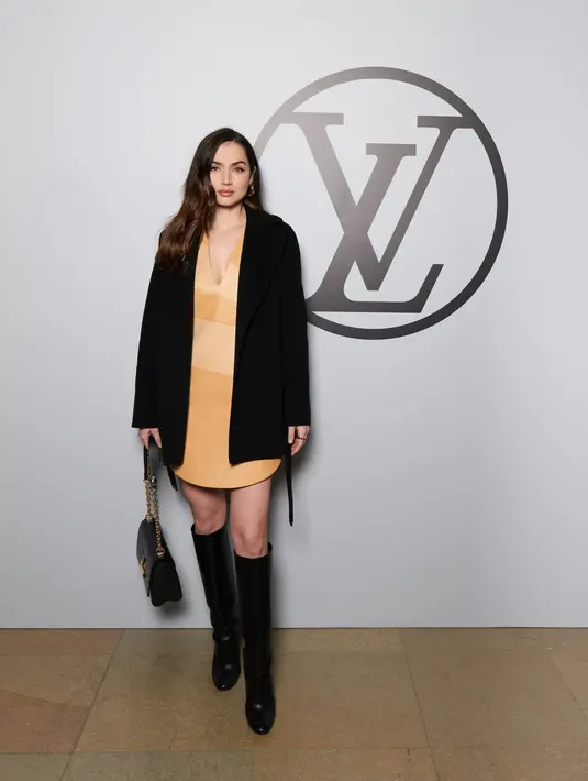 Ana de Armas tampil effortless nan elegan dengan round v-neck dress, outer hitam, dan high boots [Louis Vuitton]