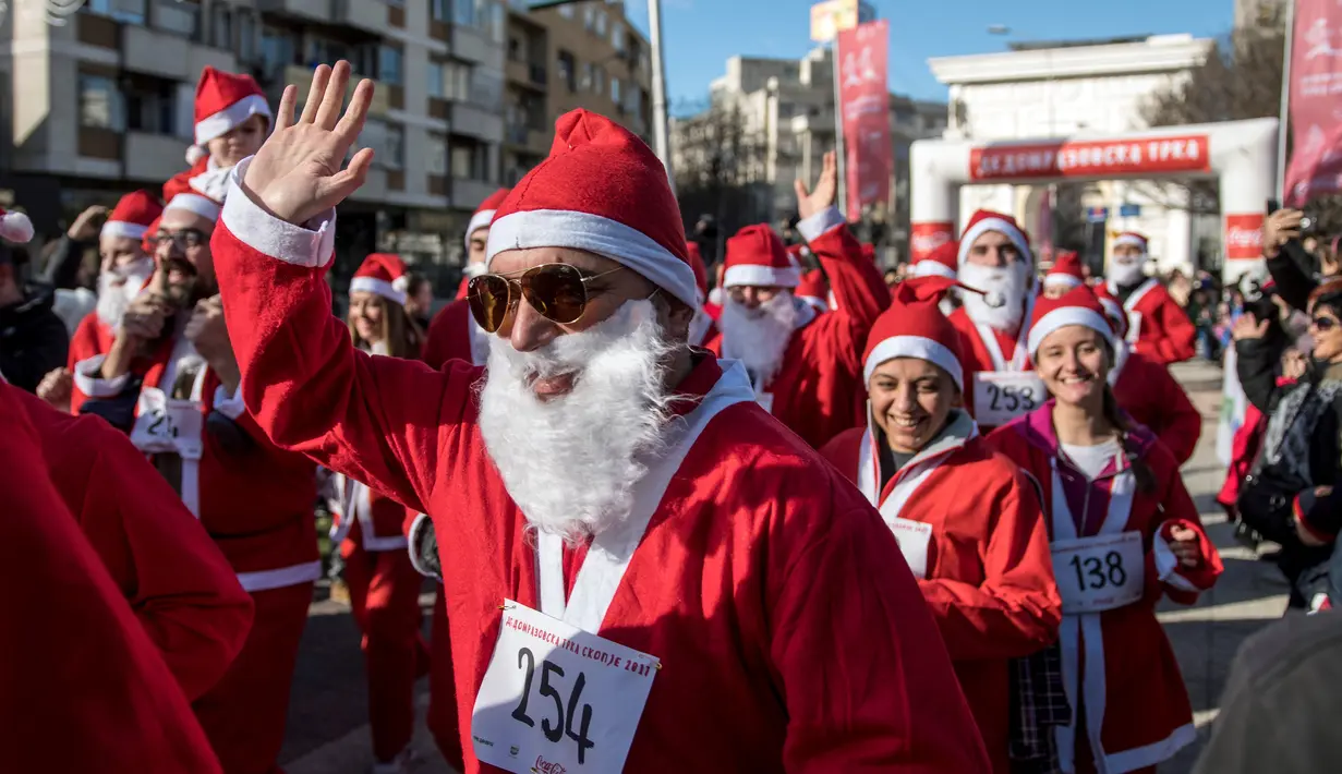 Seorang pria berpakaian Santa Claus melambaikan tangan saat mengikuti perlombaan lari tradisional Santa Claus Tahun Baru di Skopje, (24/12) (AFP Photo / Robert Atanasovki)