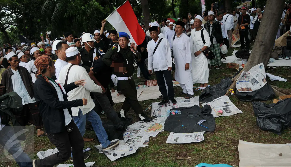 Polisi Militer Angkatan Laut menangkap seorang pria yang diduga provokator dalam aksi damai 2 Desember di kawasan Monas, Jakarta, Jumat (2/12). Pria ini sempat dipukuli hingga mengalami luka di bagian kepala. (Liputan6.com/Gempur M Surya)