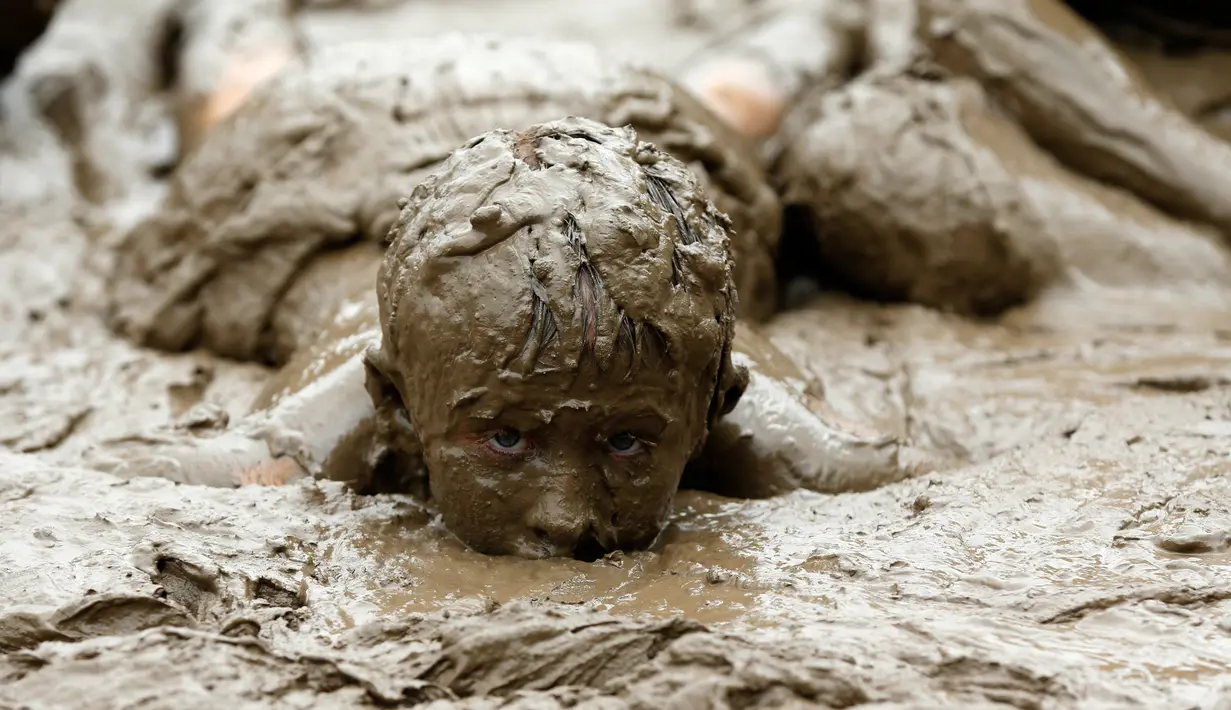 Seorang anak berendam dalam lumpur saat berpartisipasi dalam perayaan Mud Day atau Hari Lumpur di Wayne County di Nankin Mills Park, Westland, Michigan, AS (11/7). (AFP Photo/Jeff Kowalsky)