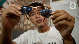Perajin Yuyud Wahyudi (39) menyelesaikan pembuatan frame kacamata dari limbah kayu bekas di Urat Kayu, Pondok Benda, Pamulang, Tangsel, Kamis (8/10/2019). Kacamata kayu hasil buatannya tersebut dijual dengan harga Rp 300 ribu hingga Rp 1,2 juta per buah. (merdeka.com/Dwi Narwoko)
