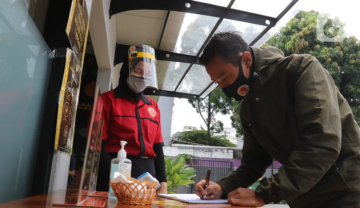 Pengunjung mengisi buku tamu sebelum memasuki restoran Bebek Kaleyo, Kemanggisan, Jakarta, Senin (12/10/2020). Pada penerapan kembali masa PSBB Transisi Jakarta, restoran dan cafe diperbolehkan melakukan pelayanan makan di tempat dengan protokol kesehatan yang ketat. (Liputan6.com/Herman Zakharia)