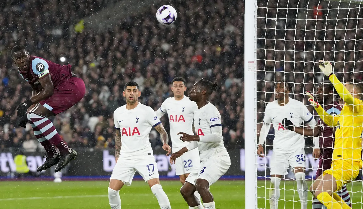 Bek West Ham United, Kurt Zouma (kiri) melepaskan sundulan yang menghasilkan gol penyeimbang 1-1 ke gawang Tottenham Hotspur pada laga pekan ke-31 Premier League 2023/2024 di London Stadium, London, Selasa (2/4/2024) malam. (AP Photo/Kirsty Wigglesworth)
