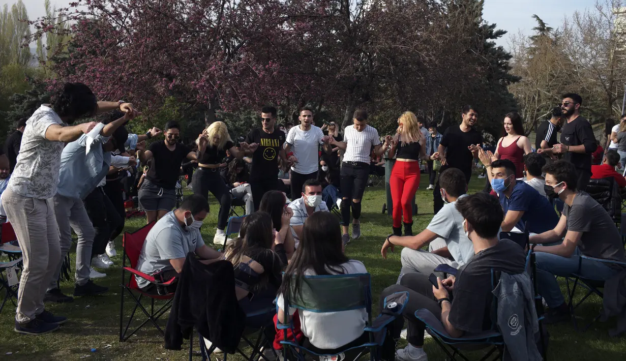 Orang-orang menari di sebuah taman di Ankara, sehari sebelum penerapan "penguncian penuh" atau lockdown, Rabu (28/4/2021). Turki akan memberlakukan lockdown penuh selama tiga minggu dari 29 April hingga 17 Mei 2021 untuk membendung penyebaran virus corona. (AP Photo/Burhan Ozbilici)