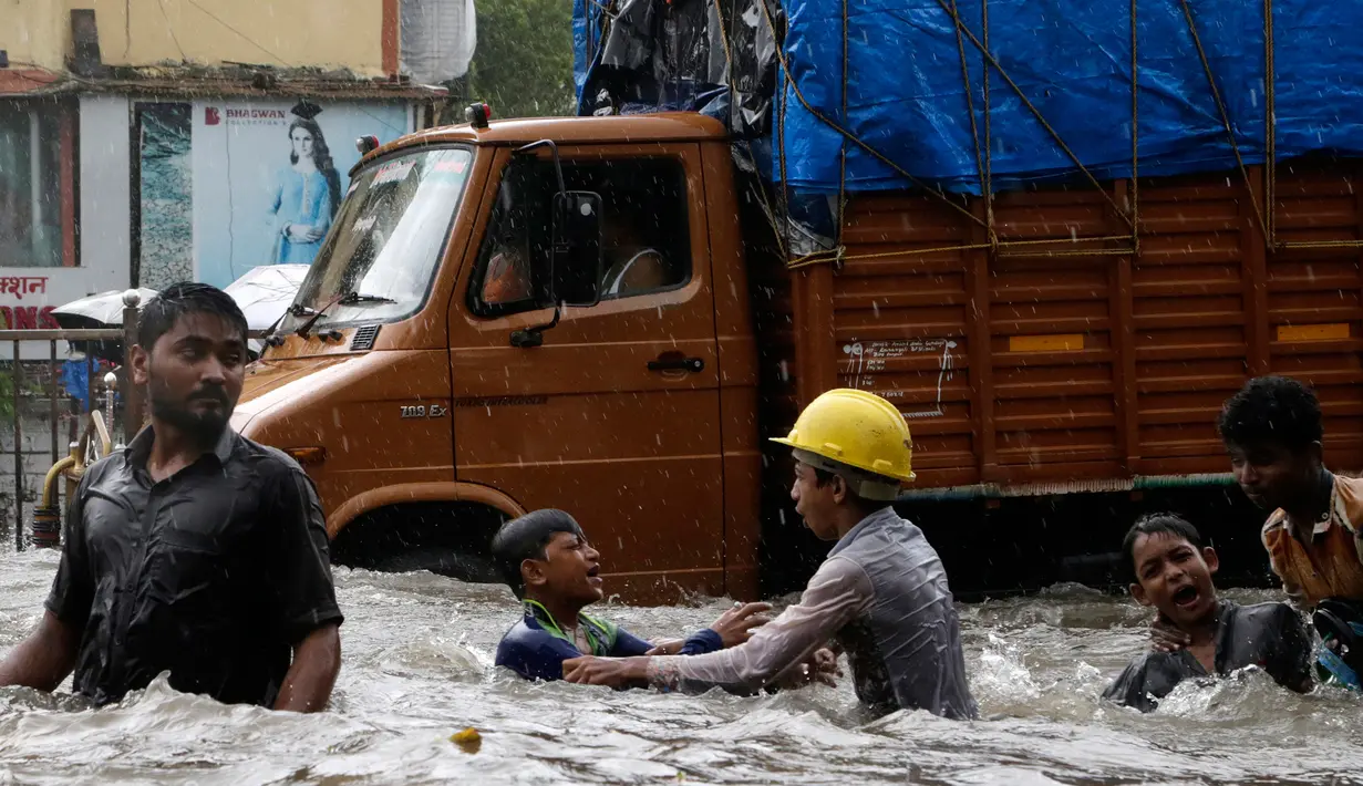 Anak-anak bermain air di jalanan yang banjir akibat hujan lebat di Mumbai, India, Selasa (29/8). Badan Bantuan Internasional menyebut meski banjir telah menjadi bencana langganan, musibah tahun ini merupakan yang paling buruk. (AP Photo/Rajanish Kakade)
