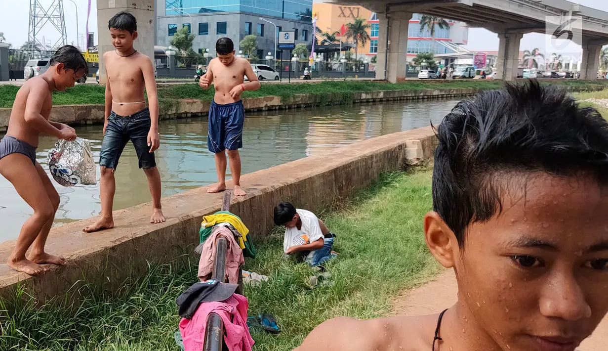 Anak-anak bermain dan berenang di Sungai Kalimalang, Jakarta Timur, Jumat (5/7/2019). Tingginya suhu udara Ibu Kota akibat musim kemarau menyebabkan anak-anak tersebut berenang di Sungai Kalimalang meski dengan kondisi seadanya. (Liputan6.com/Immanuel Antonius)