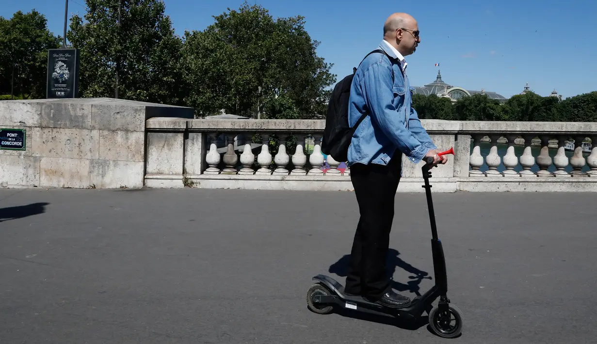 Seorang pria menggunakan skuter listrik saat beraktivitas di Paris, Prancis (9/7). Skuter listrik ini dibuat oleh perusahaan AS Lime yang merupakan penyewaan transportasi sepeda dan skuter di berbagai kota. (AFP Photo/Francois Guillot)