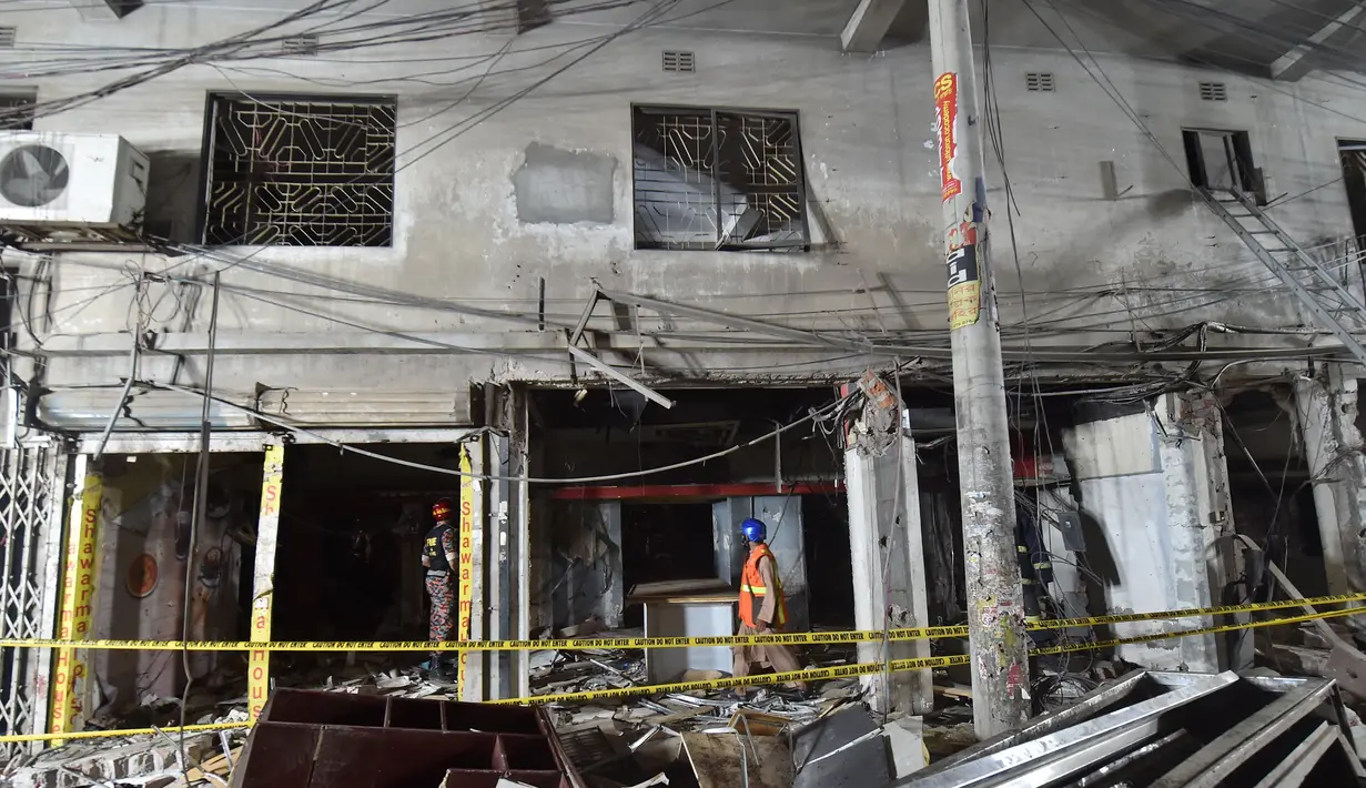 Petugas pemdam kebakaran memeriksa tempat kejadian setelah dugaan ledakan gas di jalanan ramai di Moghbazar, Dhaka, Bangladesh, Minggu (27/6/2021). Tujuh bangunan lain di dekatnya dan tiga bus hancur akibat ledakan. (Munir Uz zaman/AFP)