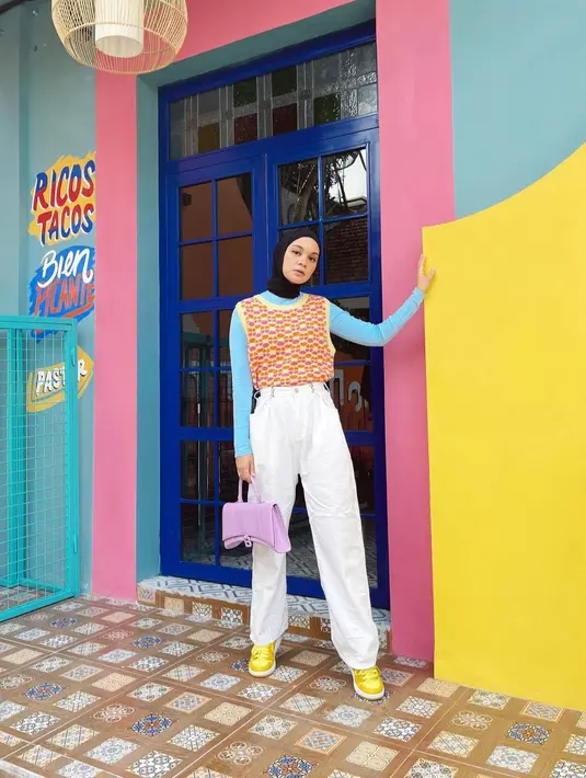 <p>Vest berwarna kuning yang bermotif dipadu padankan dengan inner berwarna biru aqua serta celana berwarna putih. (instagram/tantrinamirah)</p>