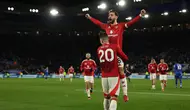 Gelandang Manchester United, Bruno Fernandes melompat ke pelukan Diogo Dalot saat merayakan gol ketiga mereka pada pertandingan pekan ke-29 Premier League 2024/2025 melawan Leicester City di King Power Stadium, Inggris pada 16 Maret 2025 waktu setempat atau Senin (17/3/2025) dini hari WIB. (Adrian Dennis/AFP)