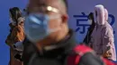 Orang-orang yang memakai masker untuk melindungi diri dari virus corona berjalan melalui distrik perbelanjaan Wangfujing di Beijing, Minggu (12/12/2021).  (AP Photo/Andy Wong)