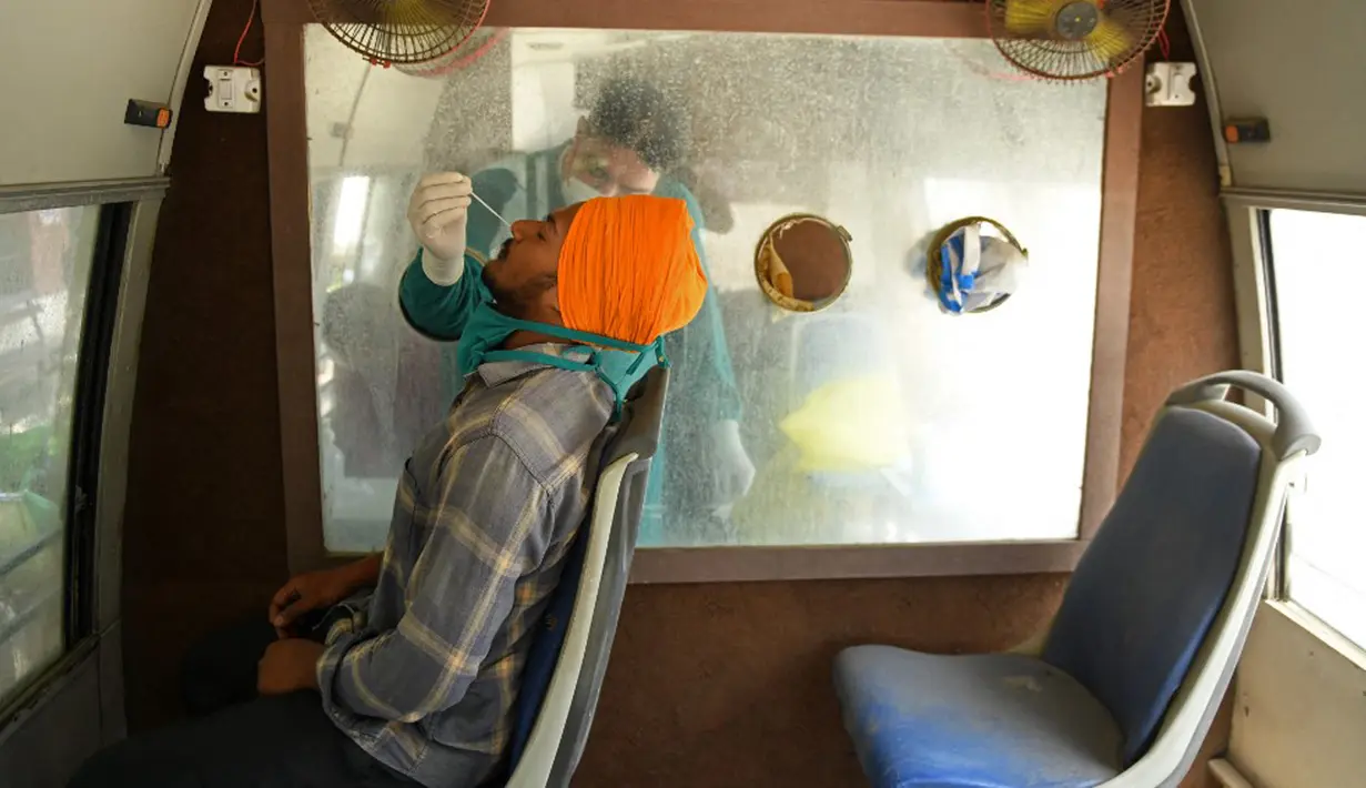 Petugas kesehatan mengumpulkan sampel usap hidung dari seorang pria untuk menguji COVID-19 dalam van pengujian seluler di Amritsar, India, Senin (24/5/2021). Kematian akibat COVID-19 di India telah menembus 300 ribu orang. (Narinder NANU/AFP)