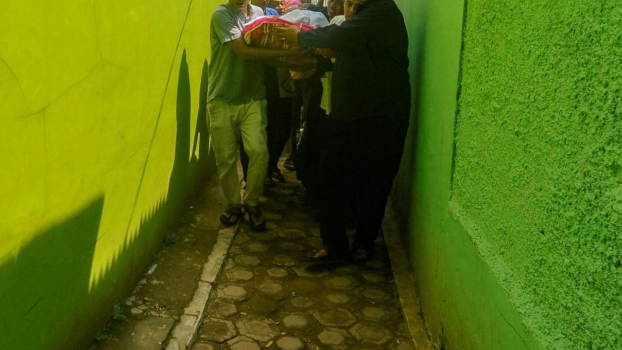 Setelah tiba diantar dengan mobil ambulans, jenazah digotong oleh warga dan keluarga dengan berjalan kaki menuju rumah duka melewati gang sempit di sebuah permukiman padat penduduk di Depok. Foto: merdeka.com / Arie Basuki