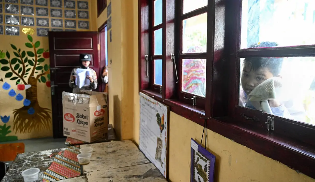 Seorang siswa melihat melalui jendela ketika teman-temannya menerima vaksin virus corona COVID-19 Sinovac di sebuah sekolah dasar di Darul Imarah, Kabupaten Aceh Besar, Provinsi Aceh, 14 Januari 2022. (CHAIDEER MAHYUDDIN/AFP)