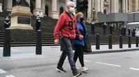 Orang-orang menyeberang jalan sementara polisi berjaga di tangga parlemen negara bagian Victoria di Melbourne, Australia, Kamis (30/9/2021). Melbourne bergulat dengan lonjakan infeksi Covid-19 di mana sebanyak 1.438 kasus dilaporkan, jumlah harian terbesar sejak awal pandemi. (William WEST / AFP)